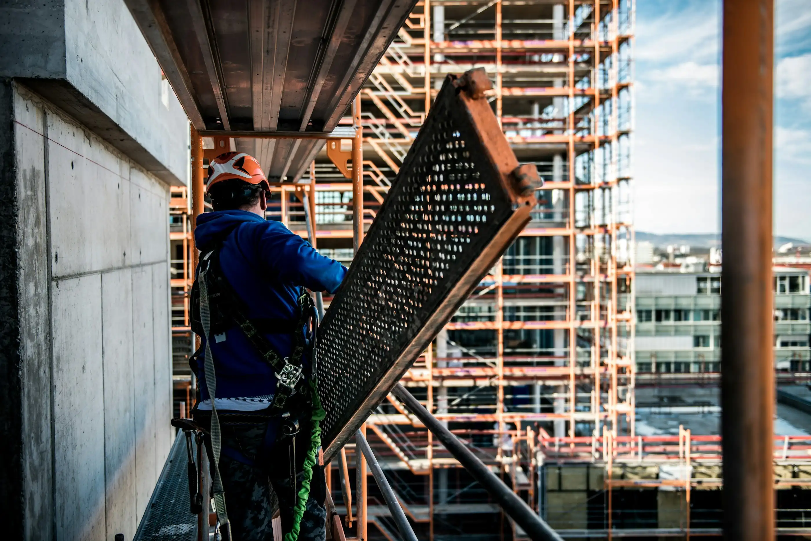Façadier de dos sur l’échafaudage, qui met en place un plancher