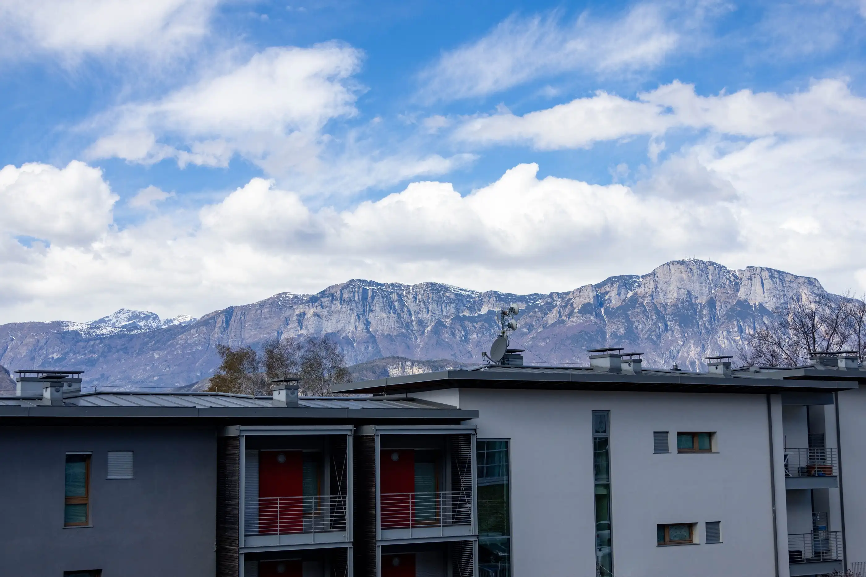 Immeuble locatif assaini, façade claire et loggias, devant la montagne