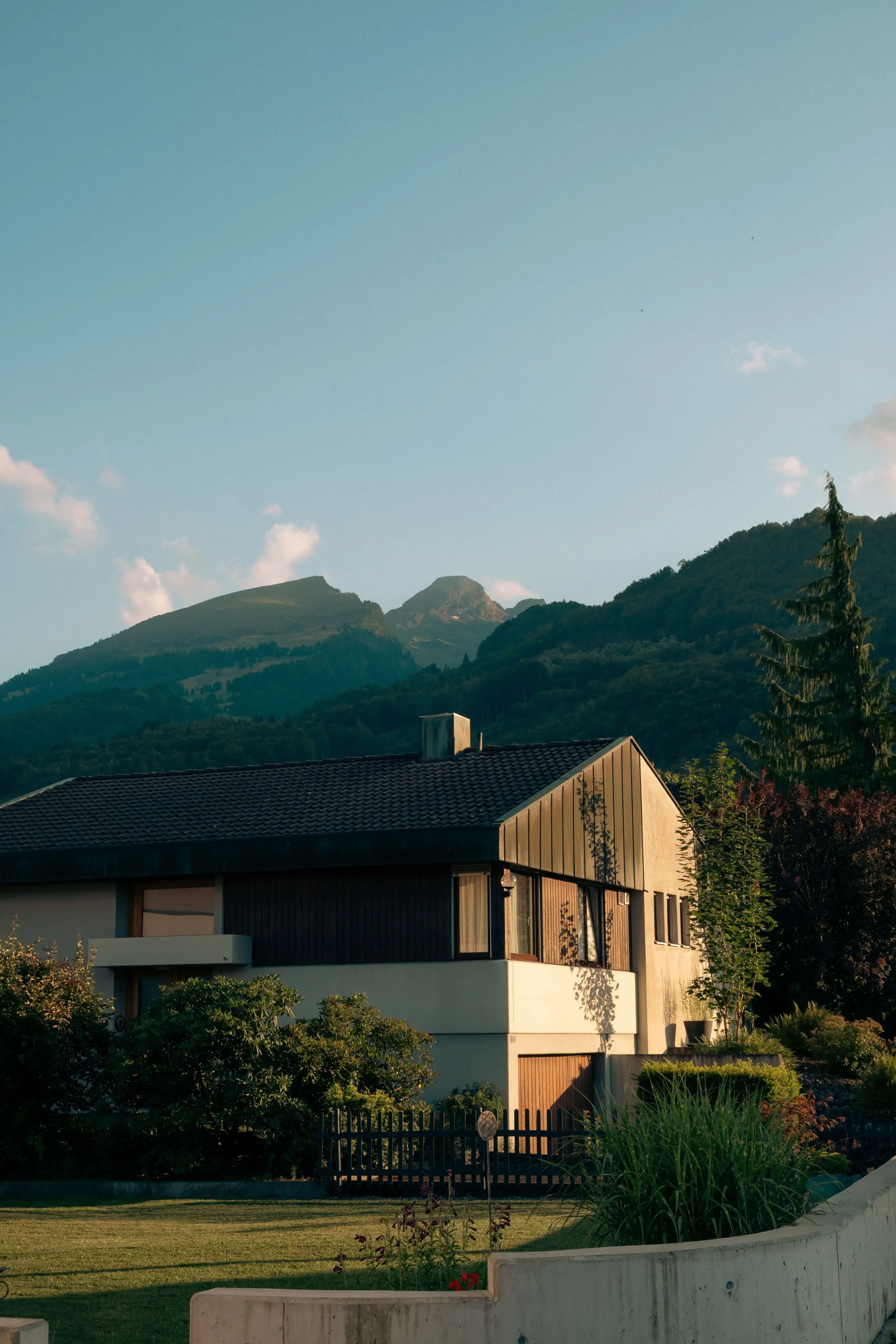 Maison individuelle crépie avec bardage bois, montagnes en arrière-plan
